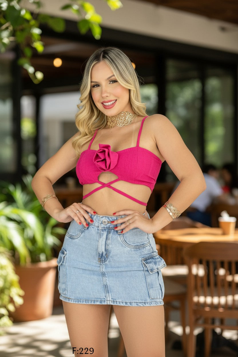 Woman in a pink top and denim skirt standing outdoors with blurred background