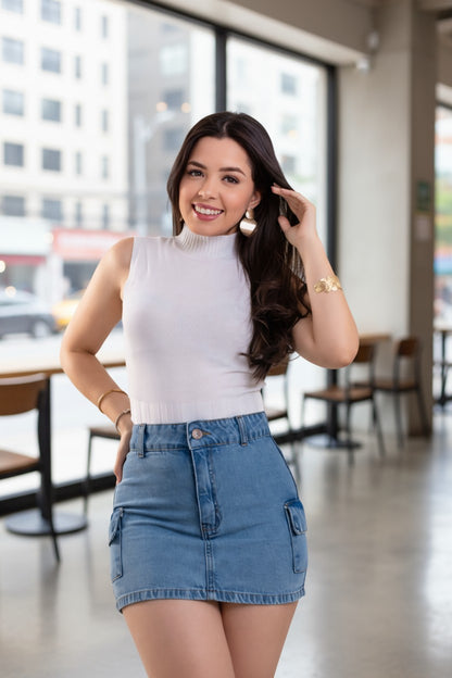 Woman in a white top and blue denim skirt standing in a cafe.